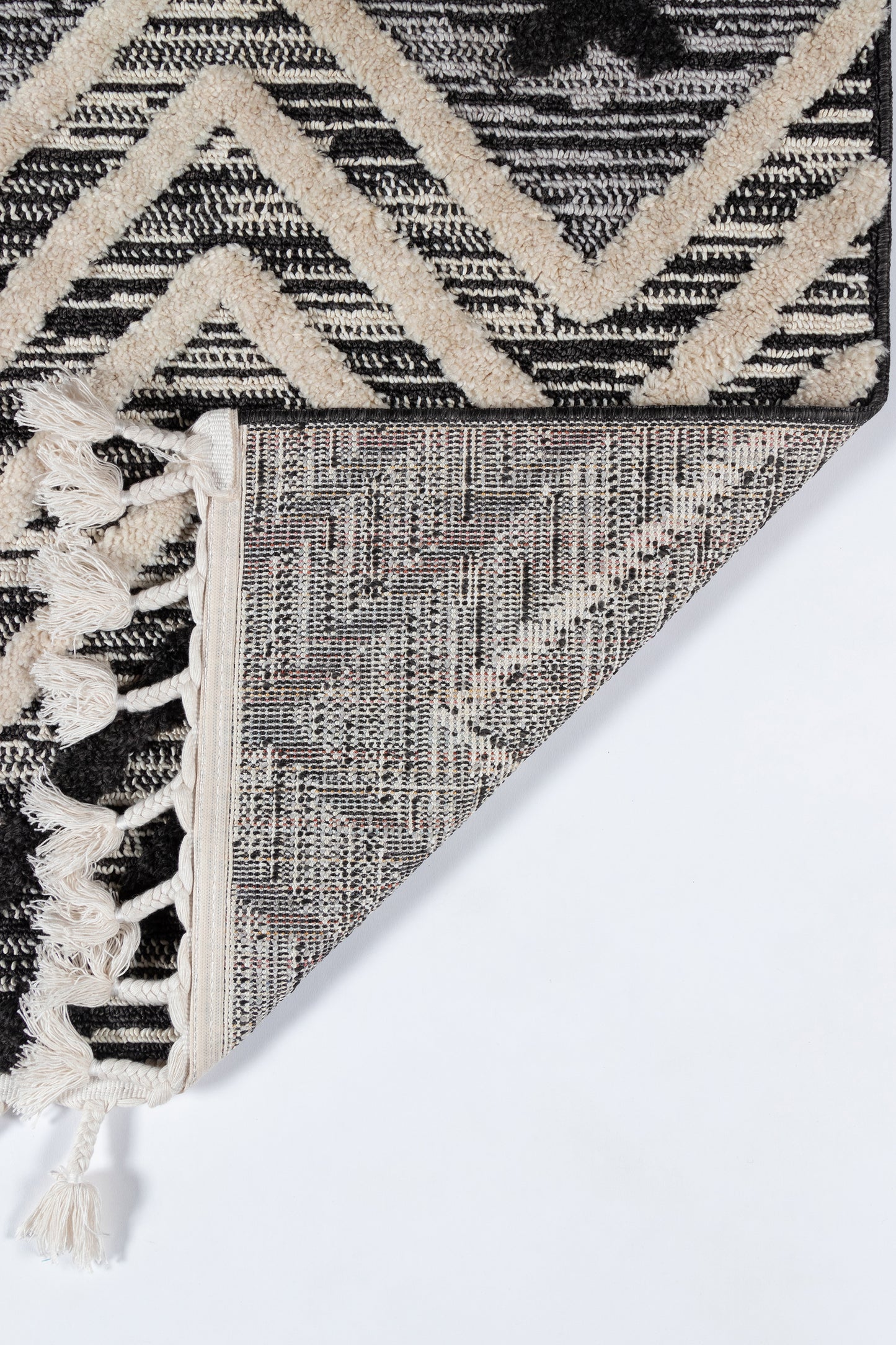 Black and ivory geometric rug with bold chevron pattern, knotted fringe, reversible woven backing.