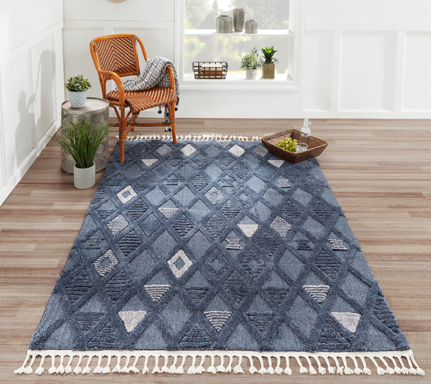 Blue geometric runner rug with diamond patterns and white tassel fringe, in a bright living room beside a wicker chair.