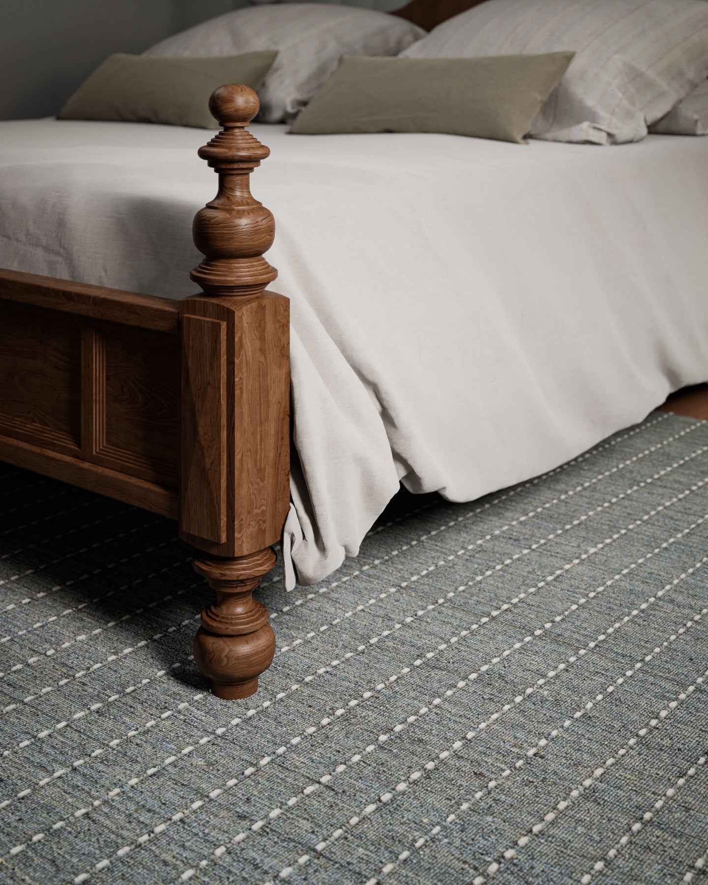 Brown stained wooden bedpost with turned finial; light gray duvet, beige pillows, and a gray striped rug.
