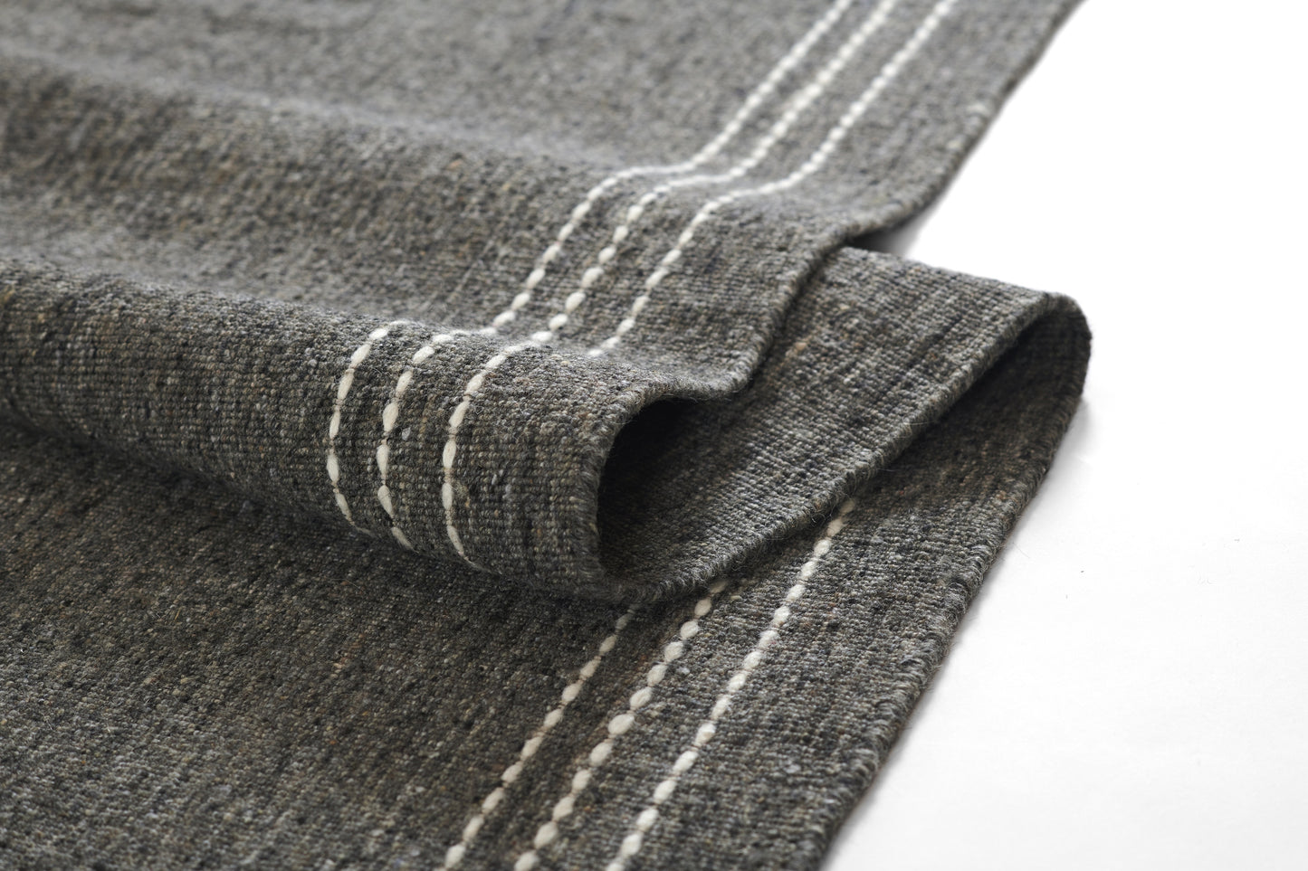 Grey textured knit fabric with white stitched seam along folded edge; casual textile.