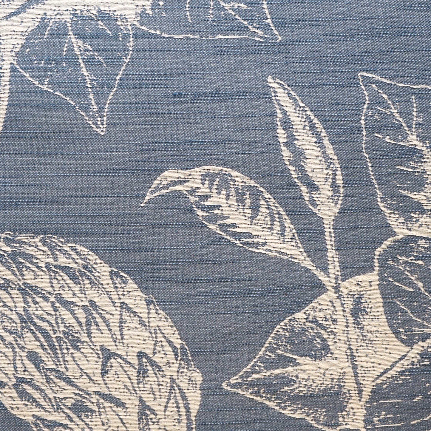 Blue woven jacquard fabric with a large white botanical leaf pattern and horizontal texture.