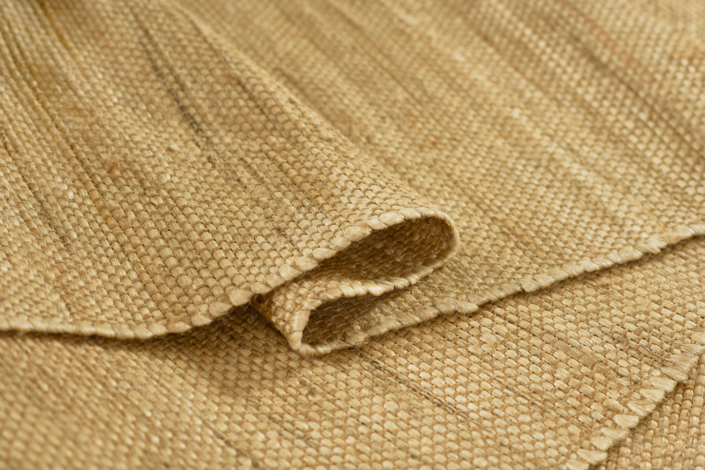 Natural burlap fabric close-up, coarse woven beige-tan jute with folded edge.