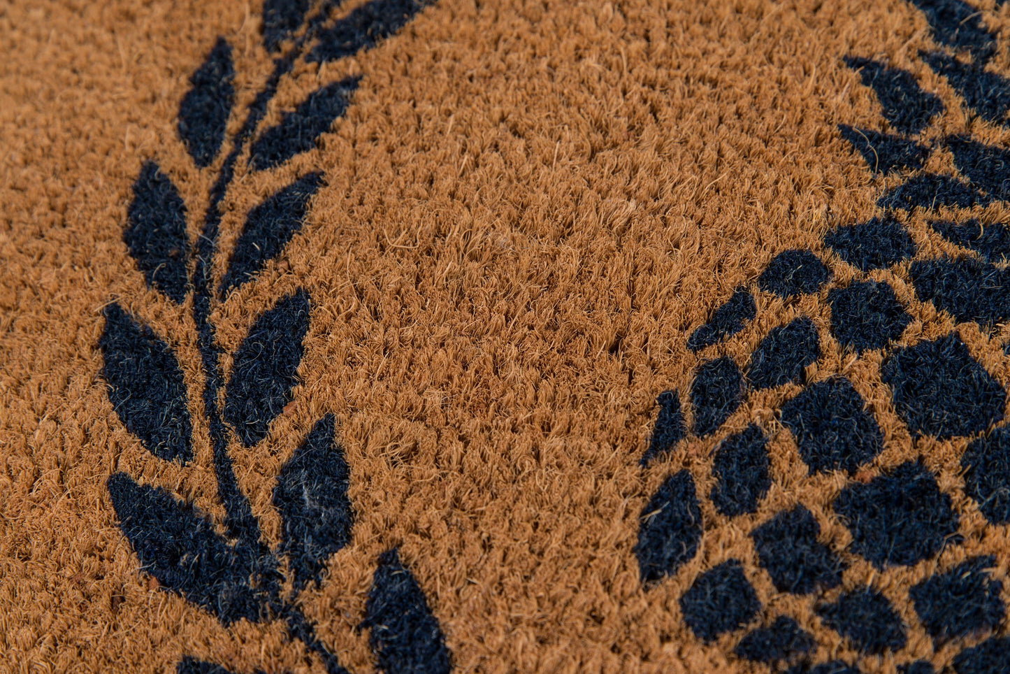 Brown coir rug with navy blue leaf and geometric pattern, textured.