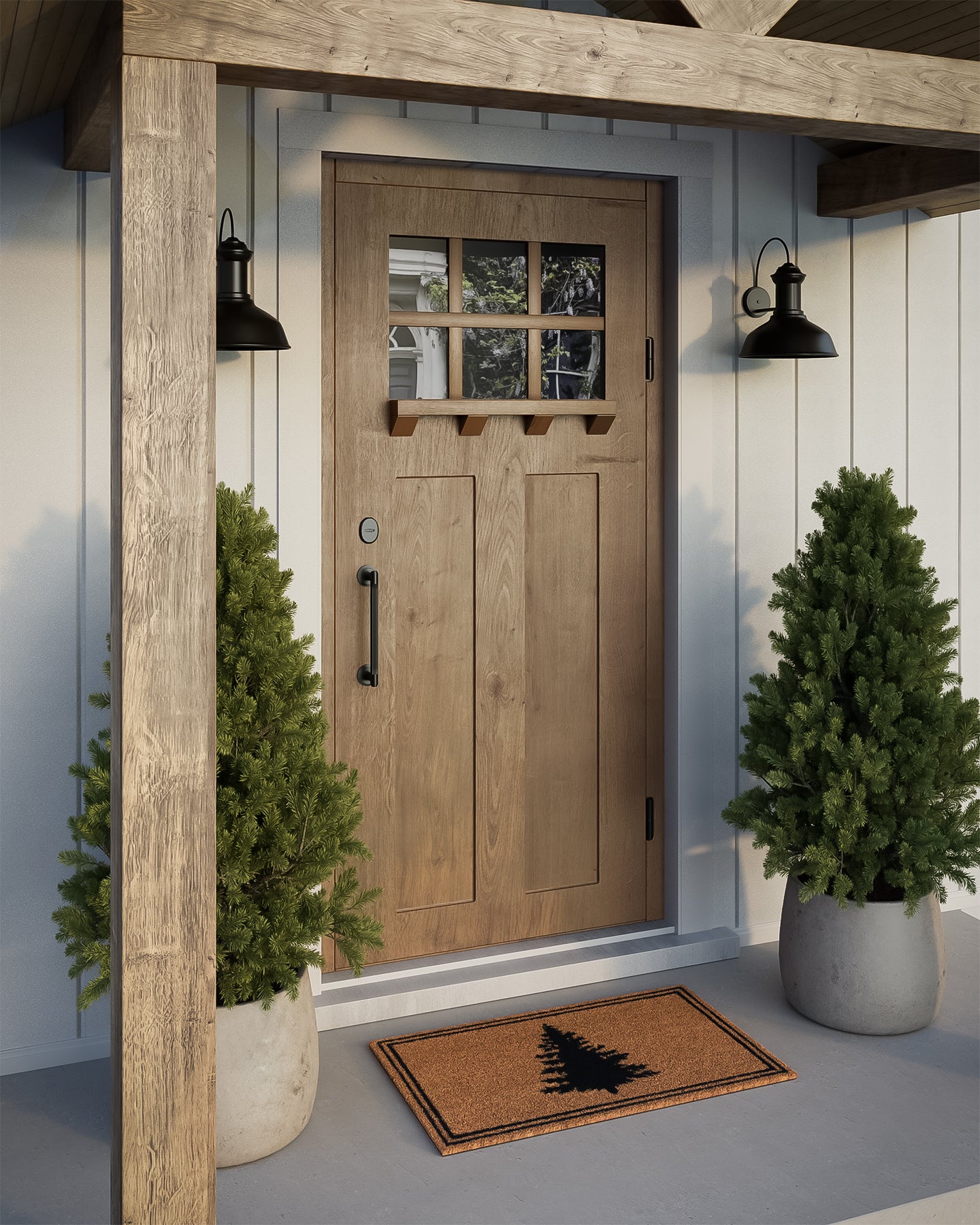 Brown wooden front door with grid window, black hardware, flanked by potted evergreens and black porch lights.