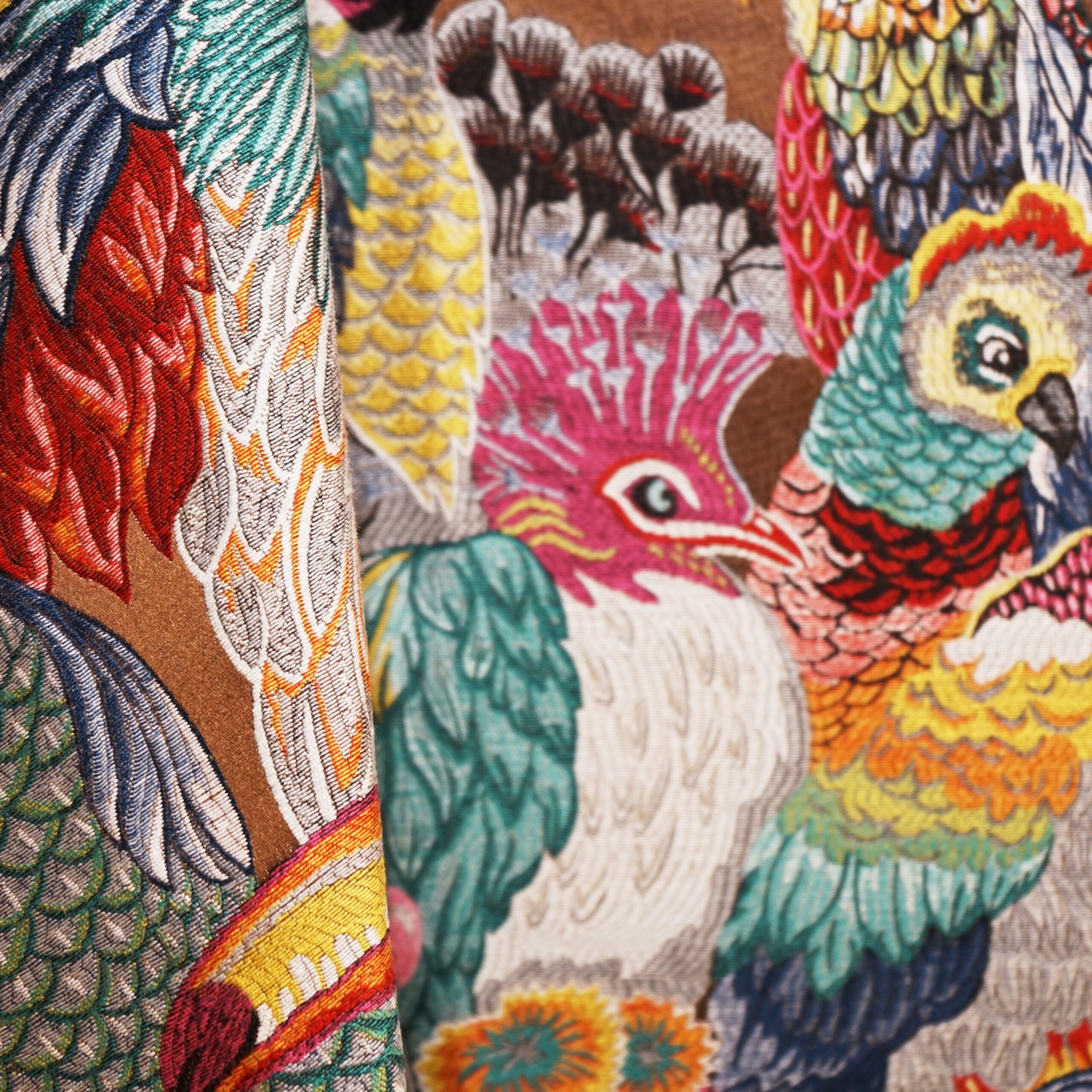 Parrot-pattern jacquard fabric with colorful birds in teal, red, yellow and pink on a brown background.