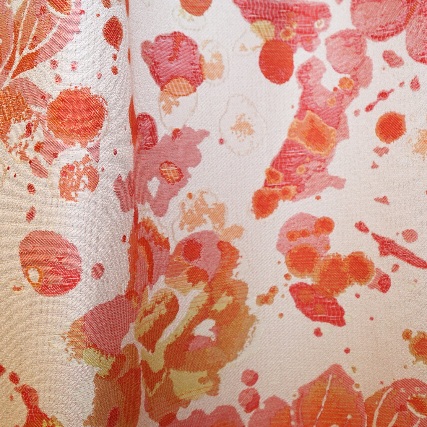Close-up of coral, peach and pink watercolor floral print on ivory fabric, soft drapey texture.