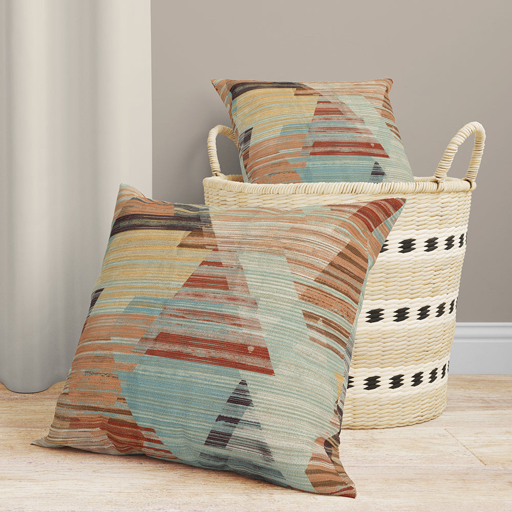 Geometric prism print fabric in teal, rust, tan & blue; woven textile with angular shapes shown draped over a wicker basket.