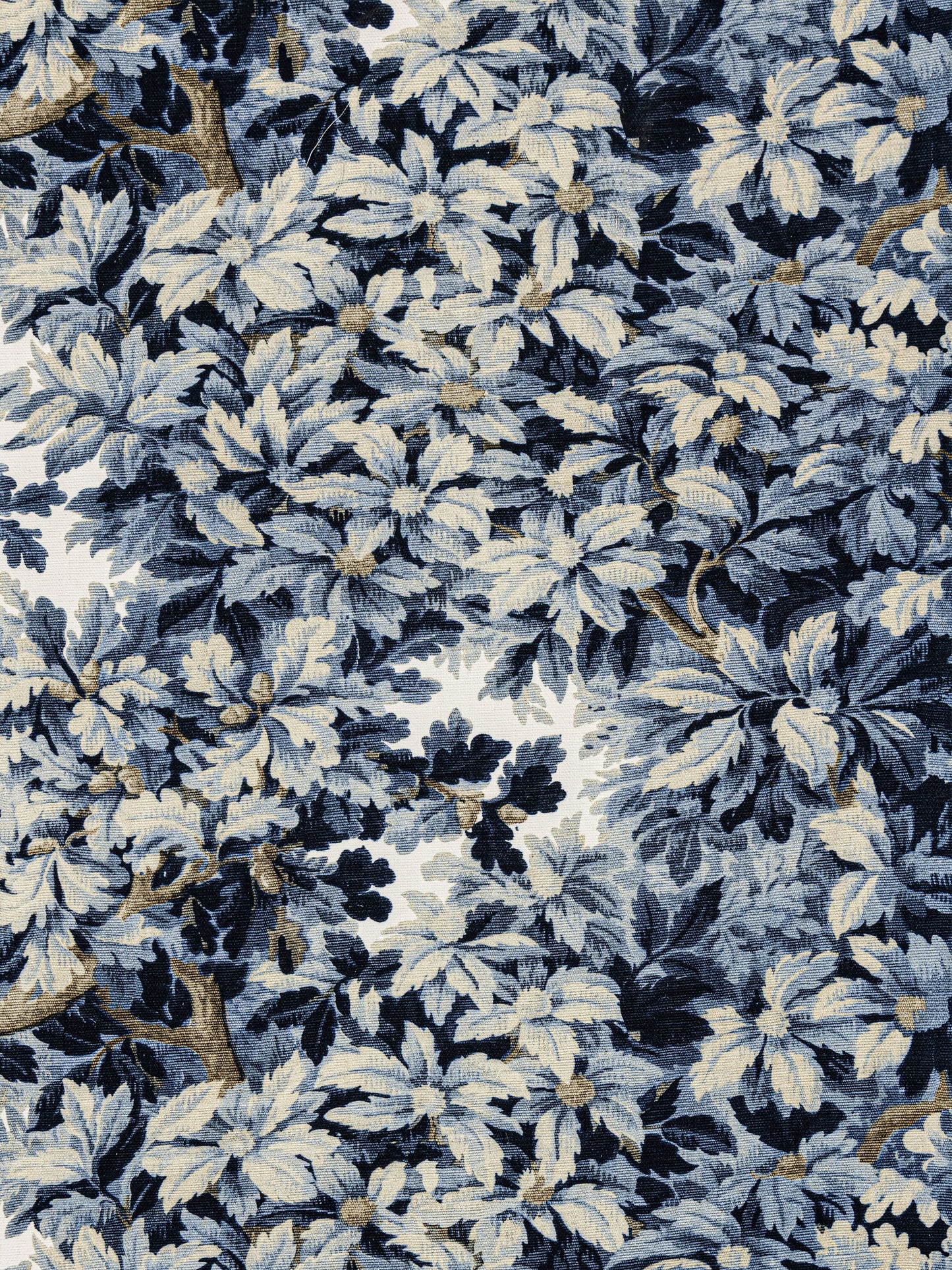 Blue and white botanical damask fabric with dense leaves, beige highlights and brown branch details.