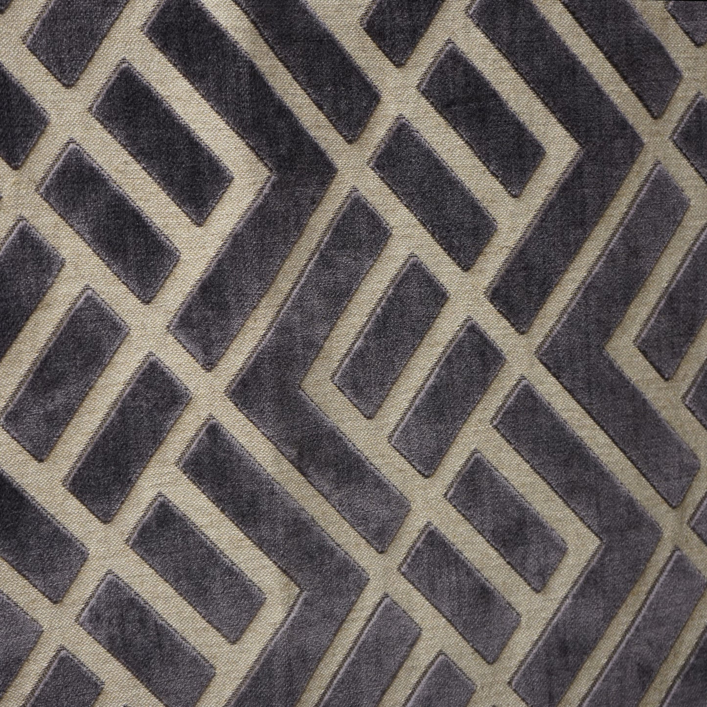 Velvet jacquard fabric swatch with an interlocking geometric lattice pattern in charcoal, creme, beige and grey.