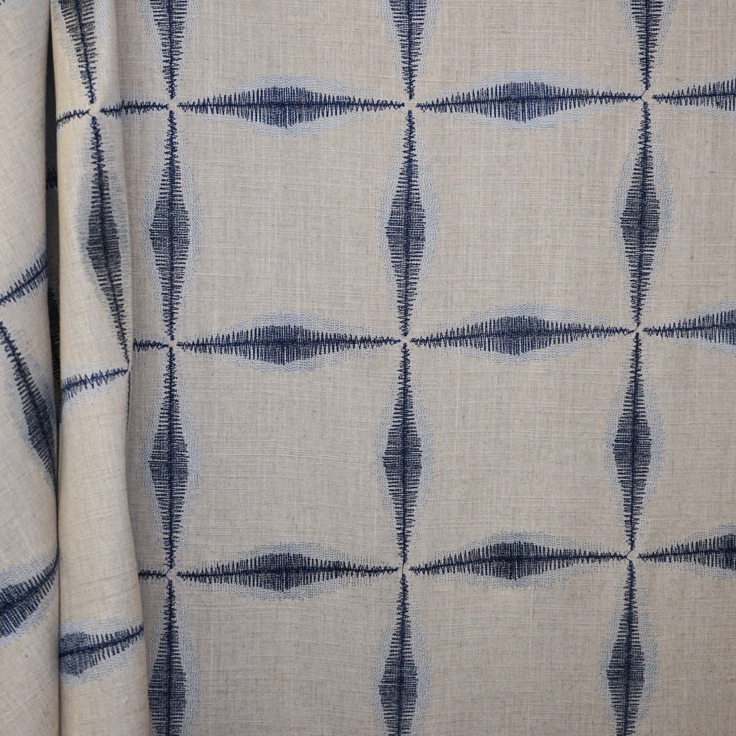 Beige linen fabric with navy geometric diamond quadrant pattern; lightweight, versatile upholstery or drapery material.