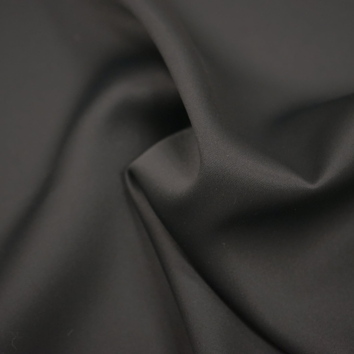 Plain black dimout lining fabric with a smooth drape.
