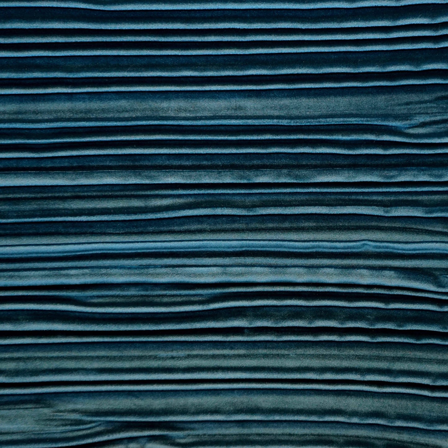 Blue velvet fabric with horizontal pleated ridges in a navy-to-teal gradient.