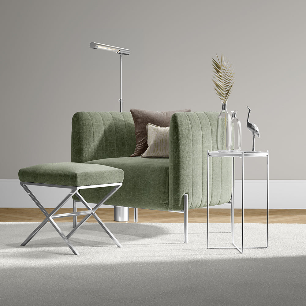 Sage green velvet sofa with rounded arms and matching ottoman, chrome legs, glass side table.