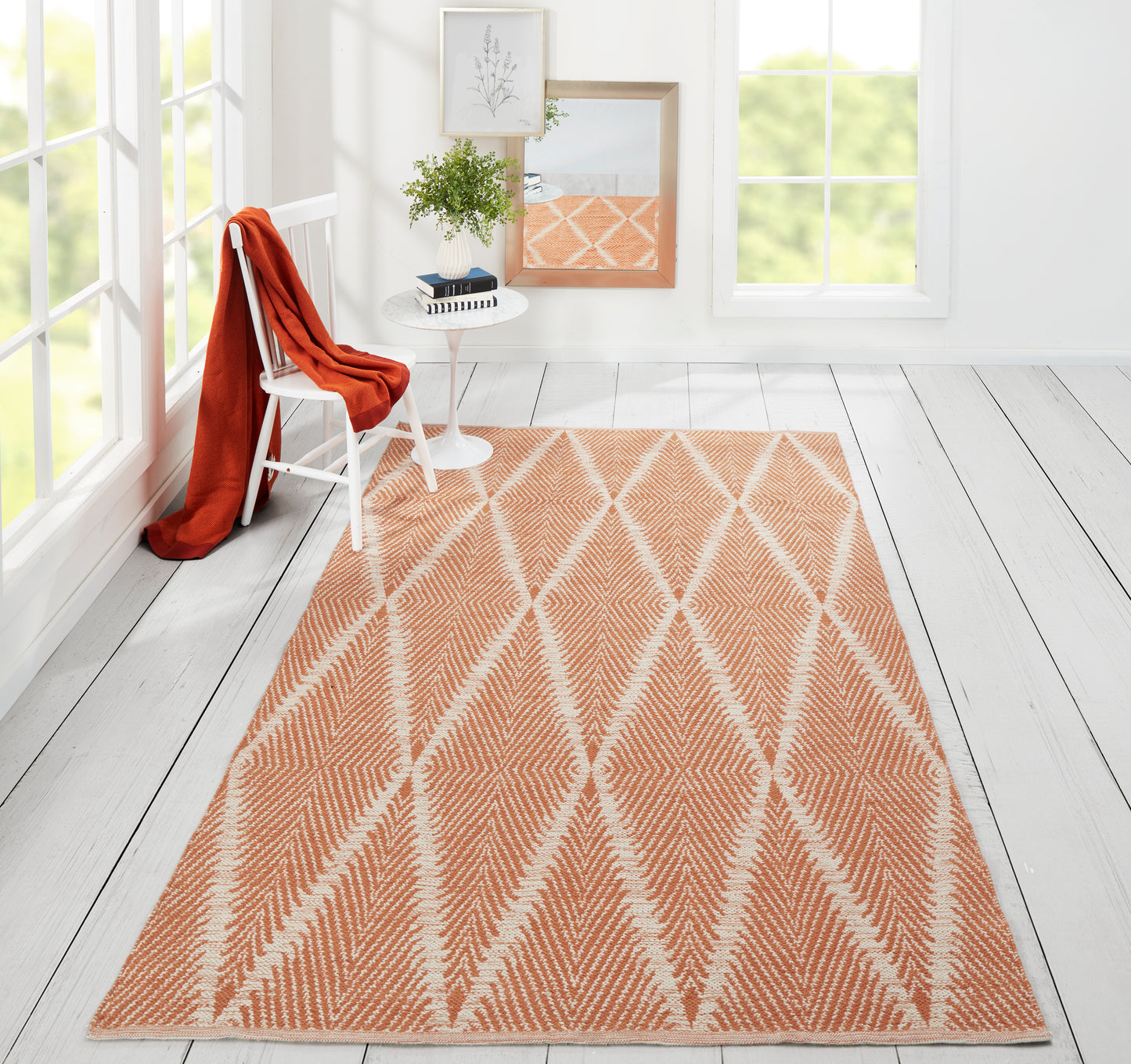 Peach-orange flat-weave rug with white diamond lattice, large rectangular floor mat in a bright, airy room.