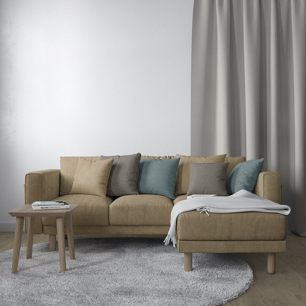 Beige fabric sectional sofa with chaise on right, teal and grey cushions, light wood legs; round coffee table, grey rug.