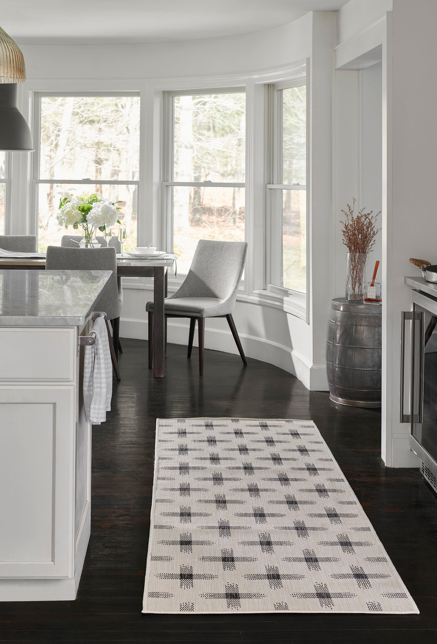 Ivory rectangular runner rug with a charcoal geometric grid pattern in a modern white kitchen & dark wood floors