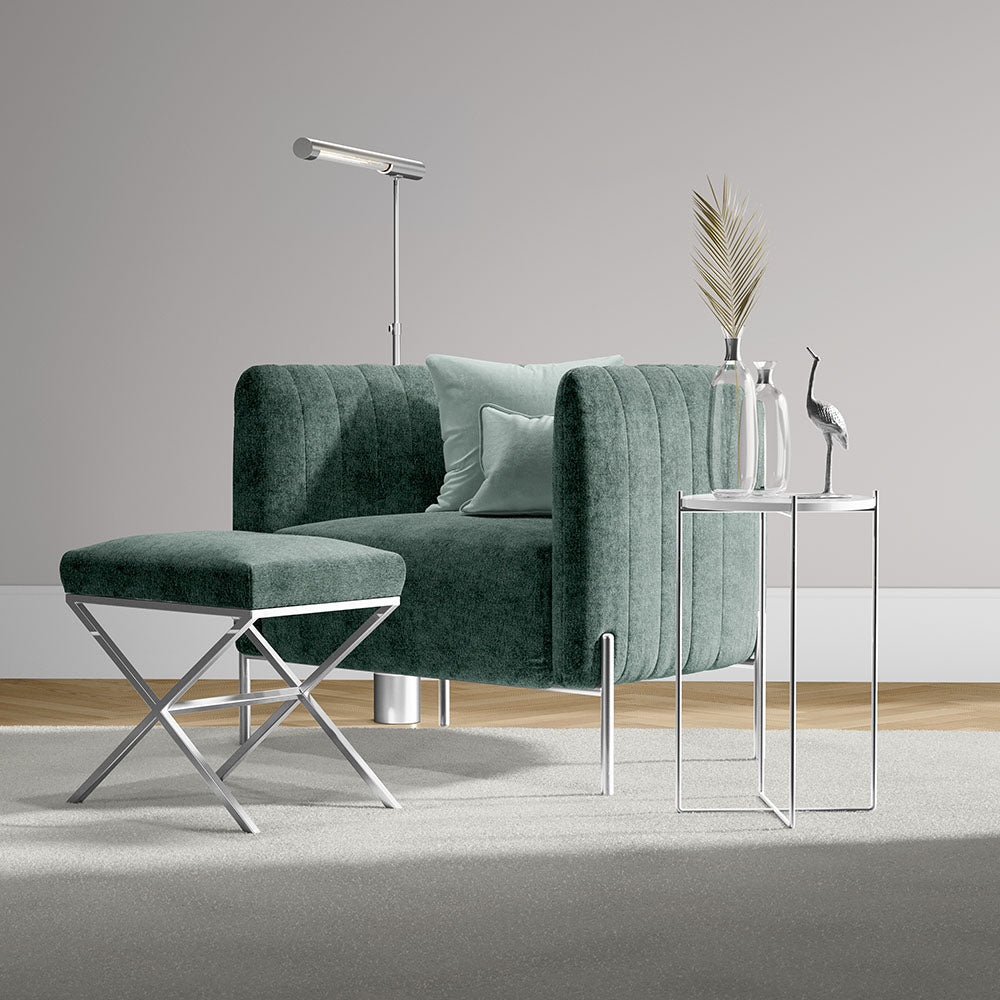 Steel blue solid fabric sofa with matching ottoman, chrome legs, glass-top side tables, and a modern floor lamp in a living room.