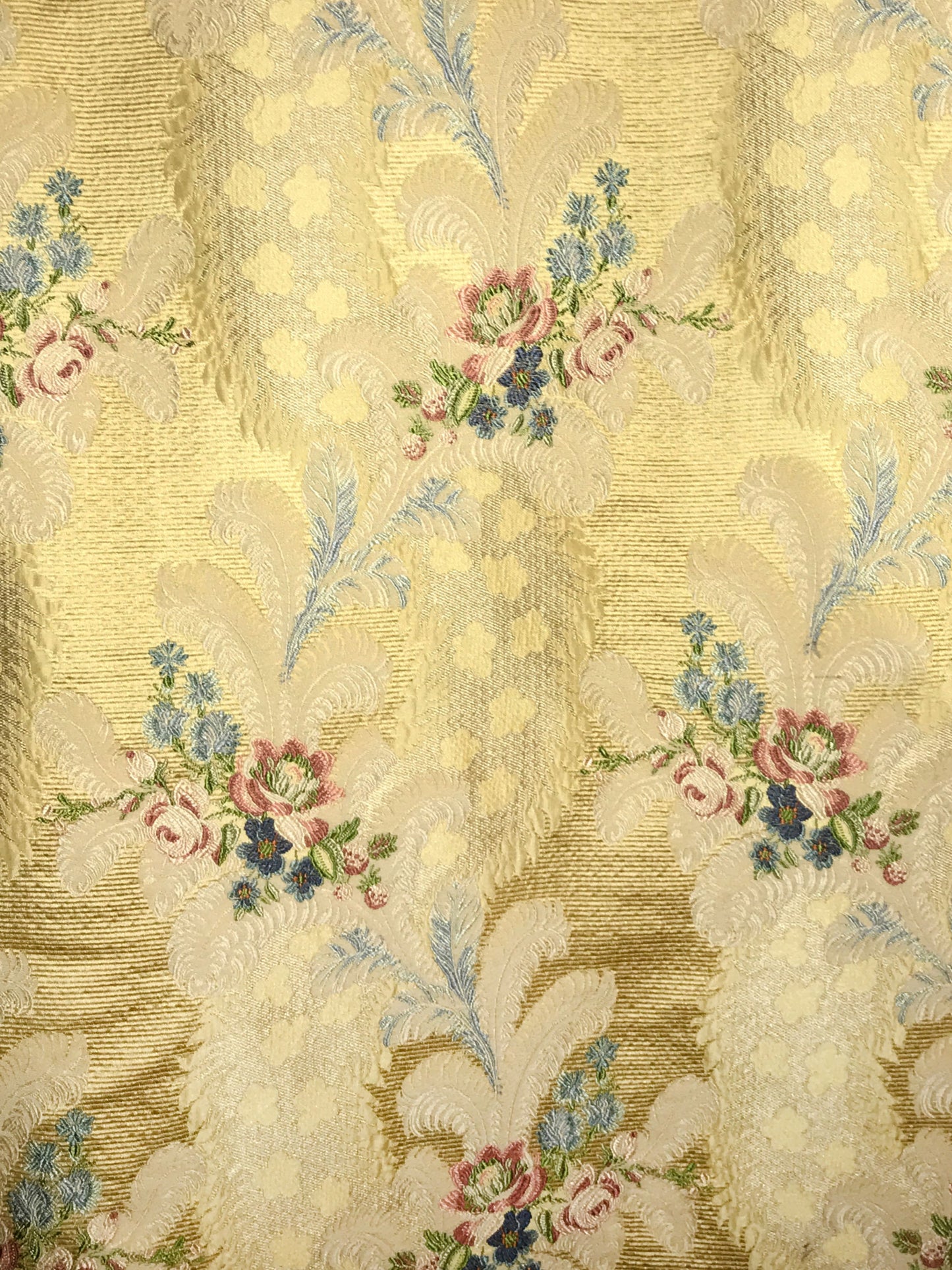 Gold damask upholstery fabric featuring pink rose bouquets and blue-green foliage in an ornate vintage floral pattern.