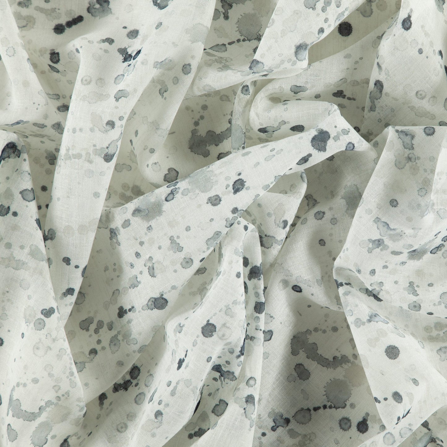 Lightweight white fabric with blue-gray ink-splatter print; sheer, drapable textile for scarves or blouses.