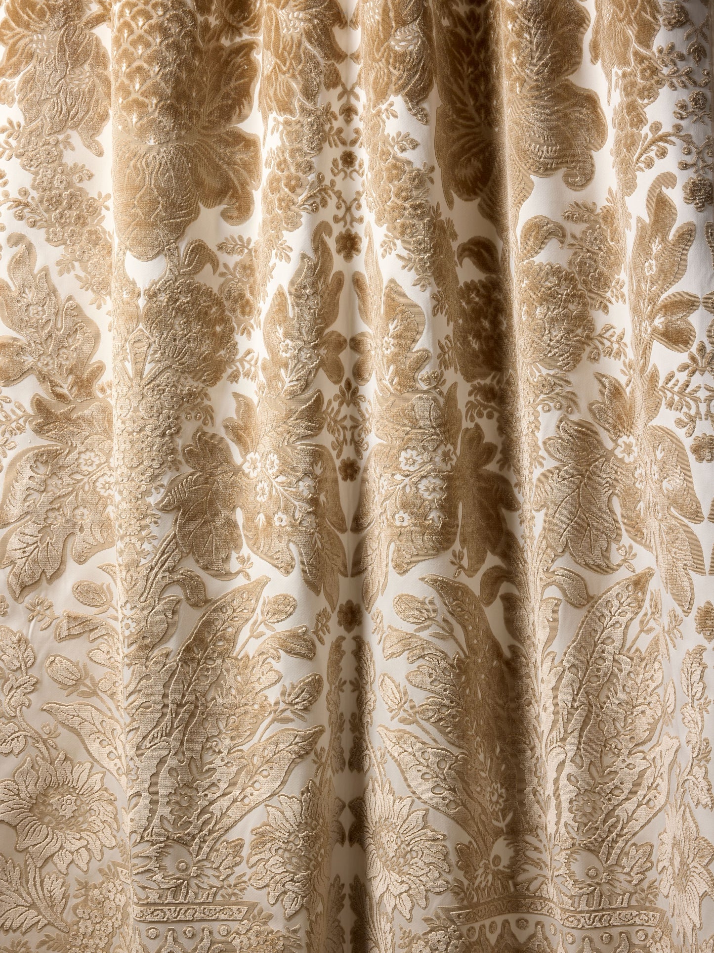 Gold and beige damask patterned curtain fabric with ornate floral motifs.