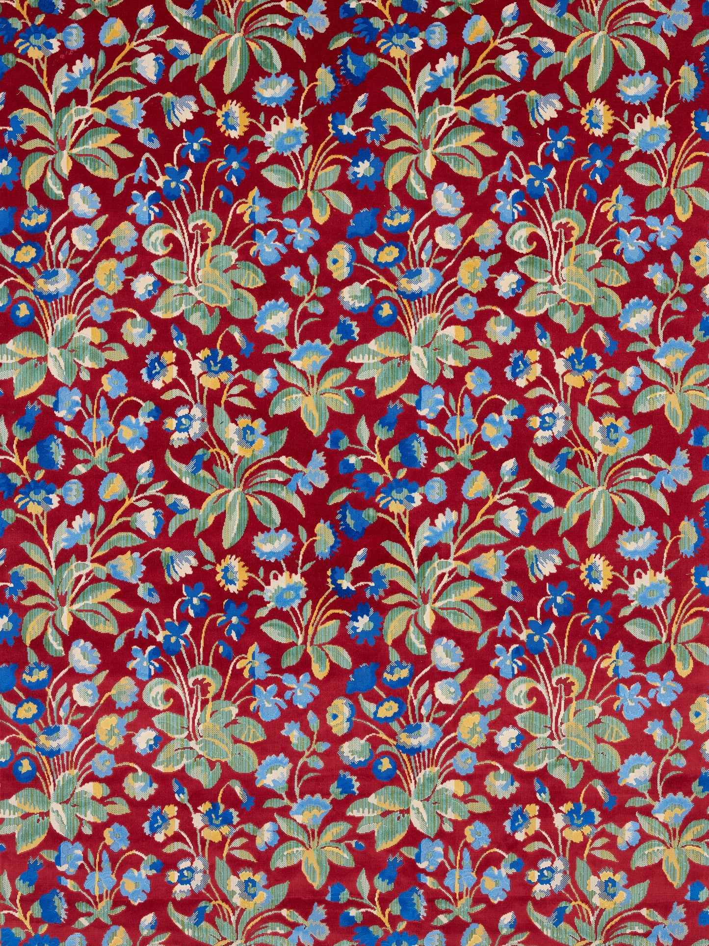Red floral textile with blue and pale yellow flowers and green leaves in a vintage tropical pattern.