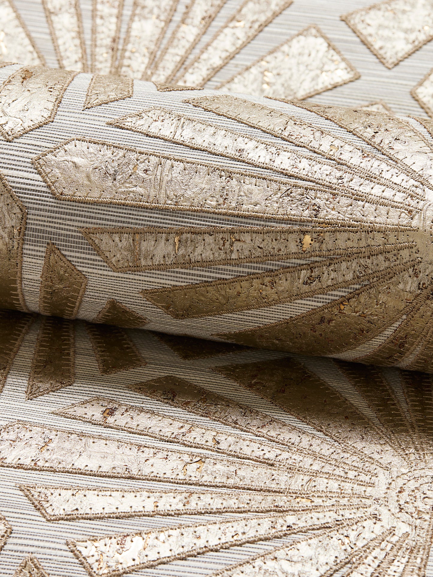 Beige textured grasscloth wallcovering with metallic gold accents; embossed, Art Deco-inspired geometric pattern.