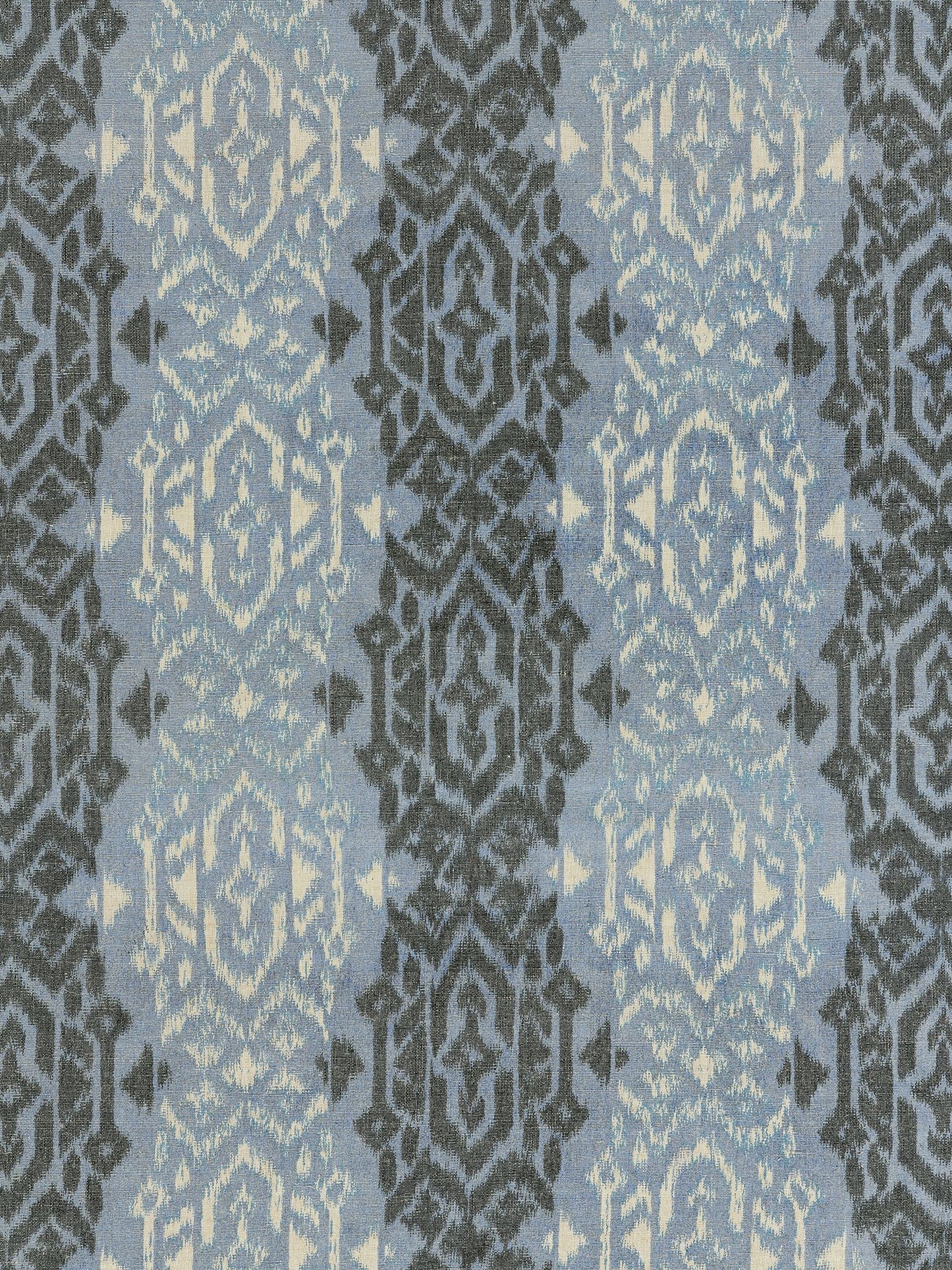 Blue woven upholstery fabric with repeating dark gray damask ikat medallions on a light blue background.