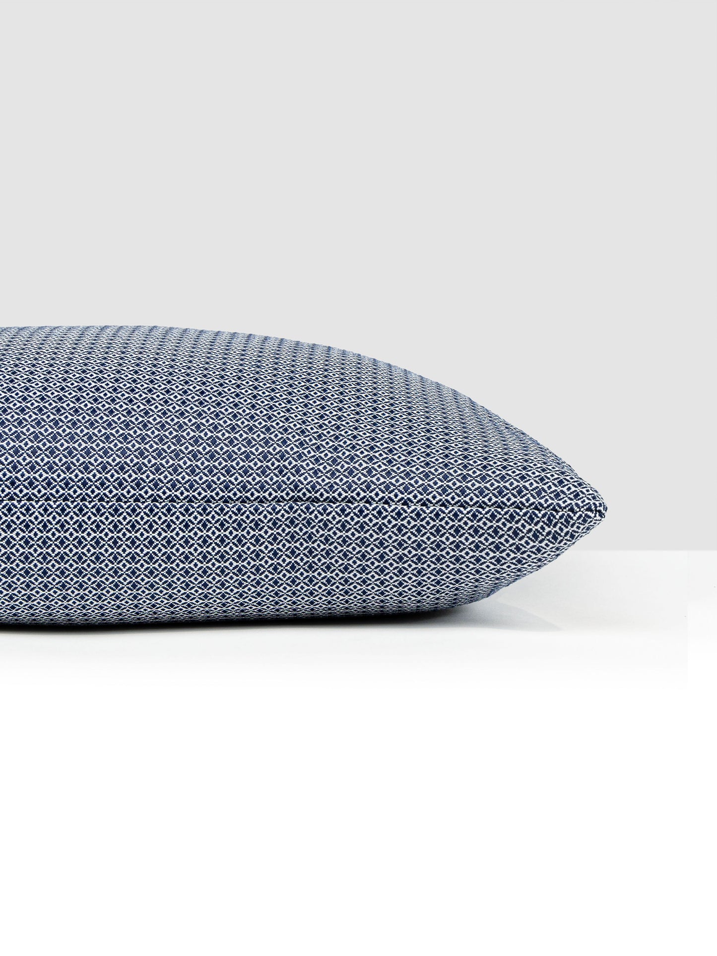 Blue geometric-patterned cushion with white diamonds, textured fabric, side view decorative throw pillow.
