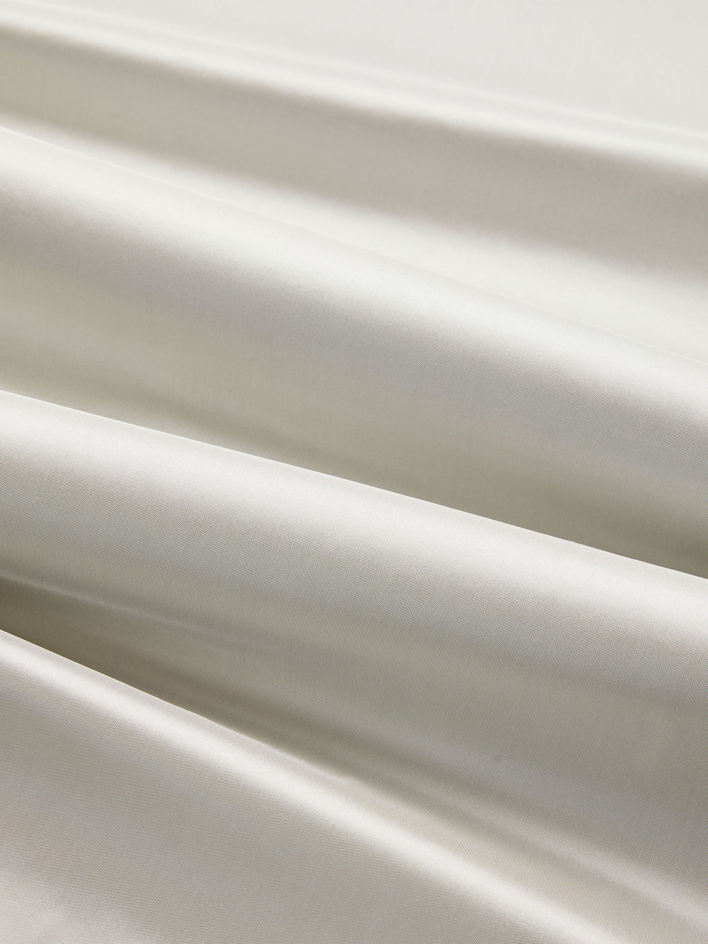 White silk taffeta fabric close-up with glossy folds and smooth drape; elegant sheen.