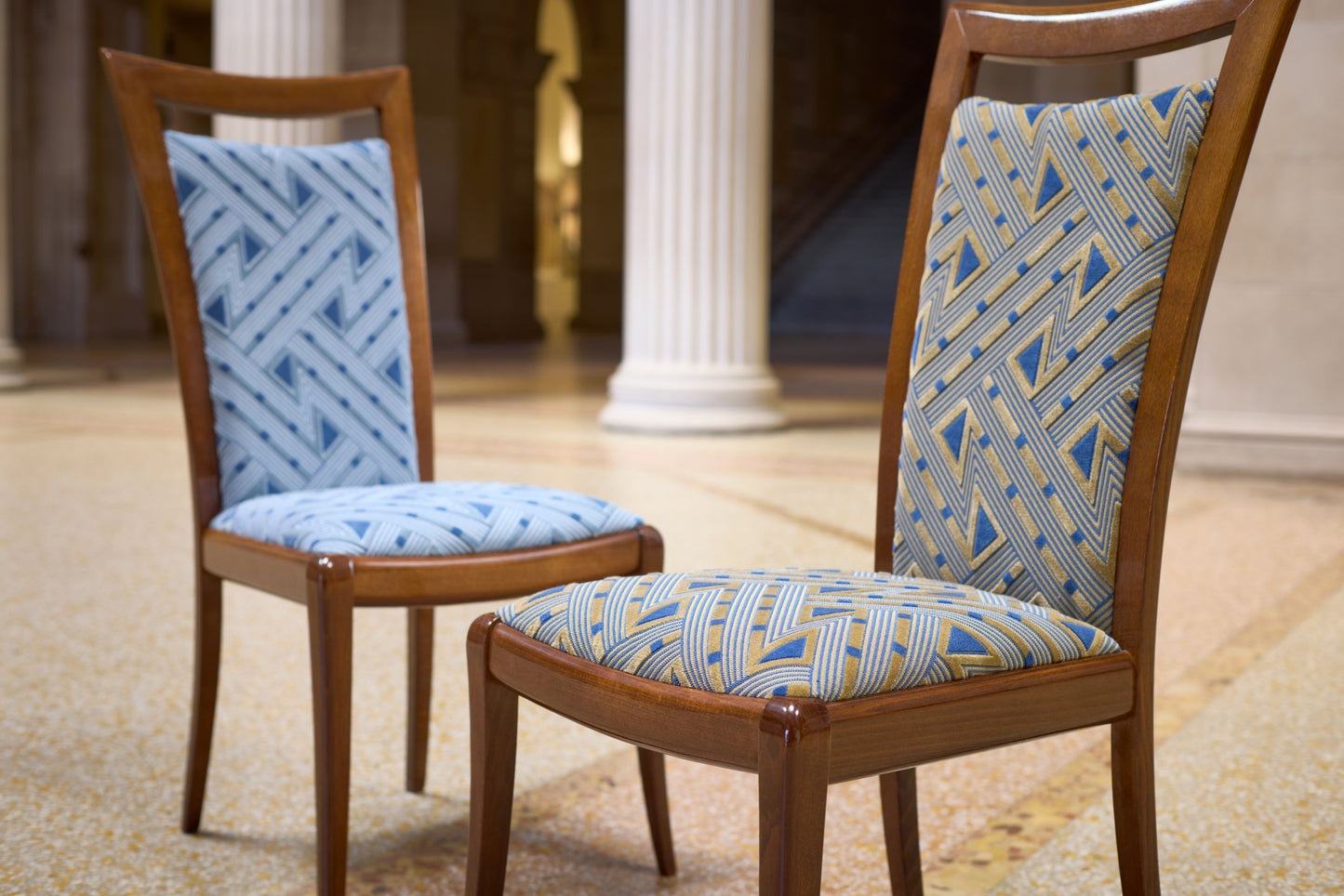 Pair of wooden dining chairs with brown frames and blue geometric patterned upholstery on seats and backs.