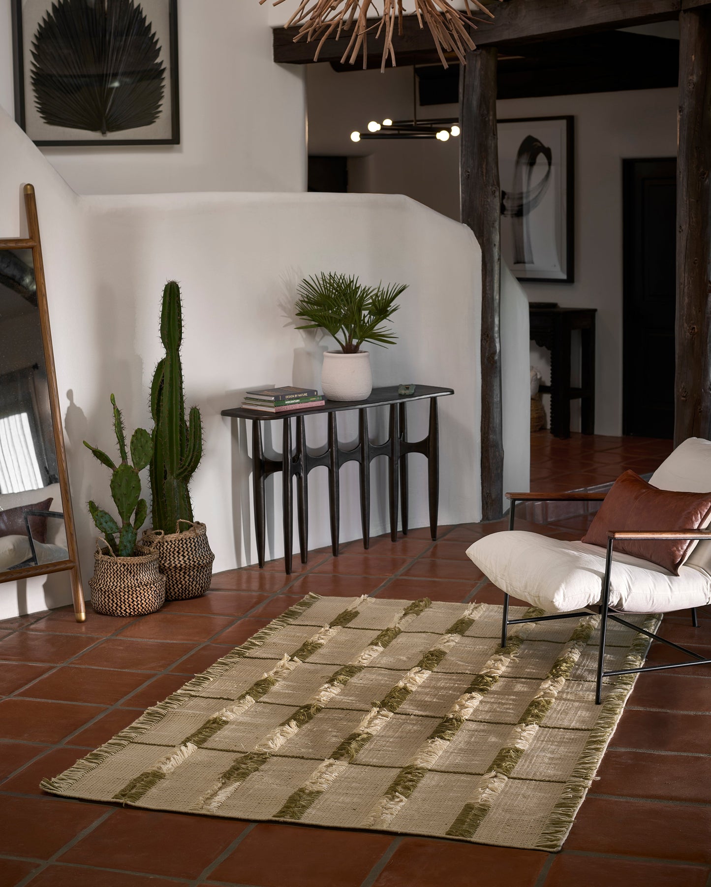Natural beige jute rug with green stripe bands on terracotta tile floor beside a modern chair.