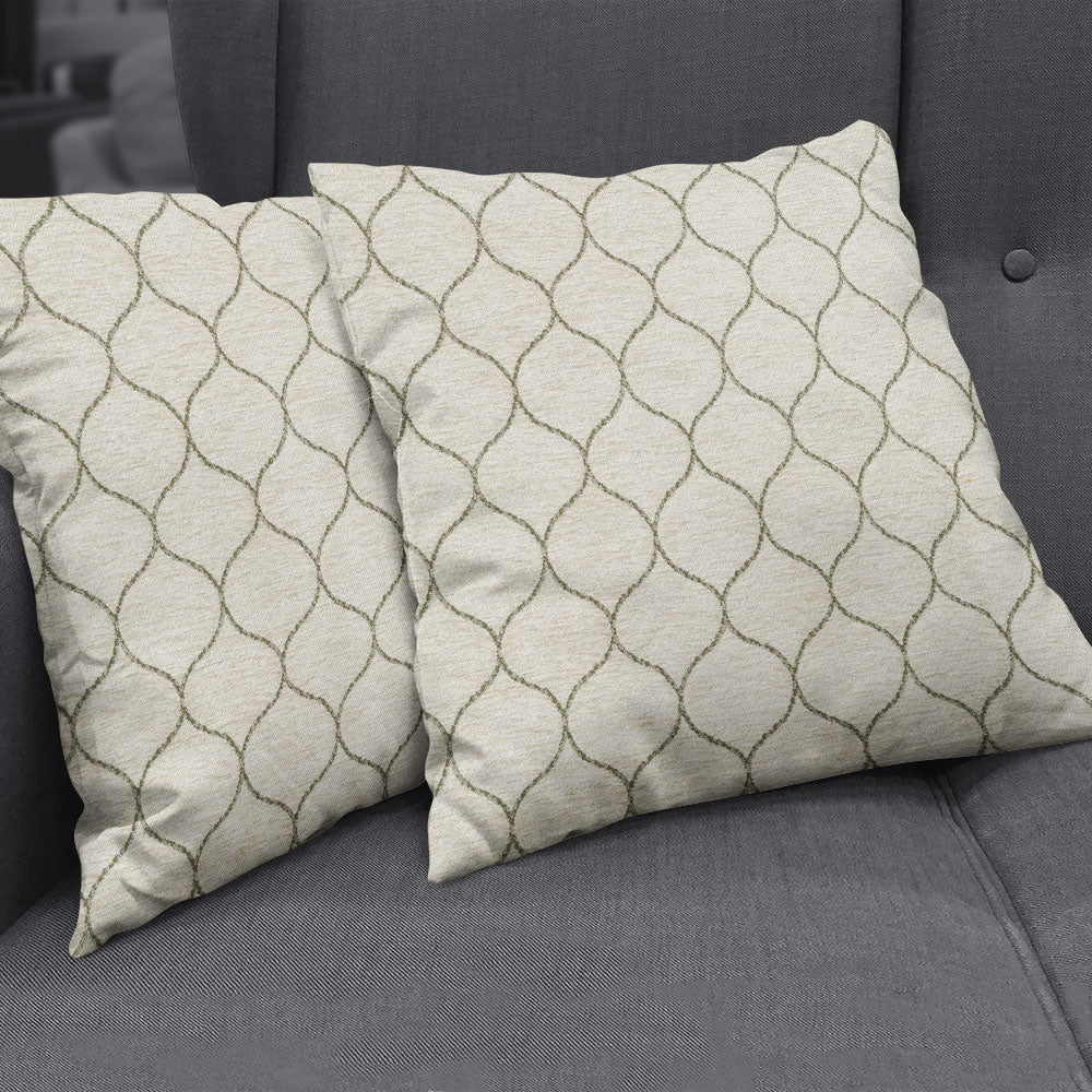 Beige square throw pillows with taupe curved lattice pattern on a gray fabric sofa.