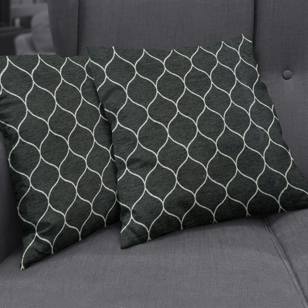 Two charcoal gray decorative pillows with a white geometric lattice pattern on a textured gray sofa, in Onyx Geometric fabric NJ25-3224.