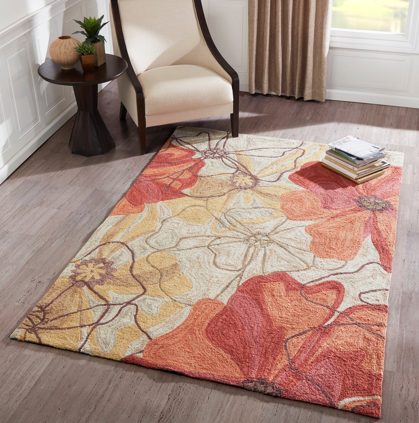 Rectangular soft plush floral rug in warm orange, yellow and cream tones under a beige upholstered chair.