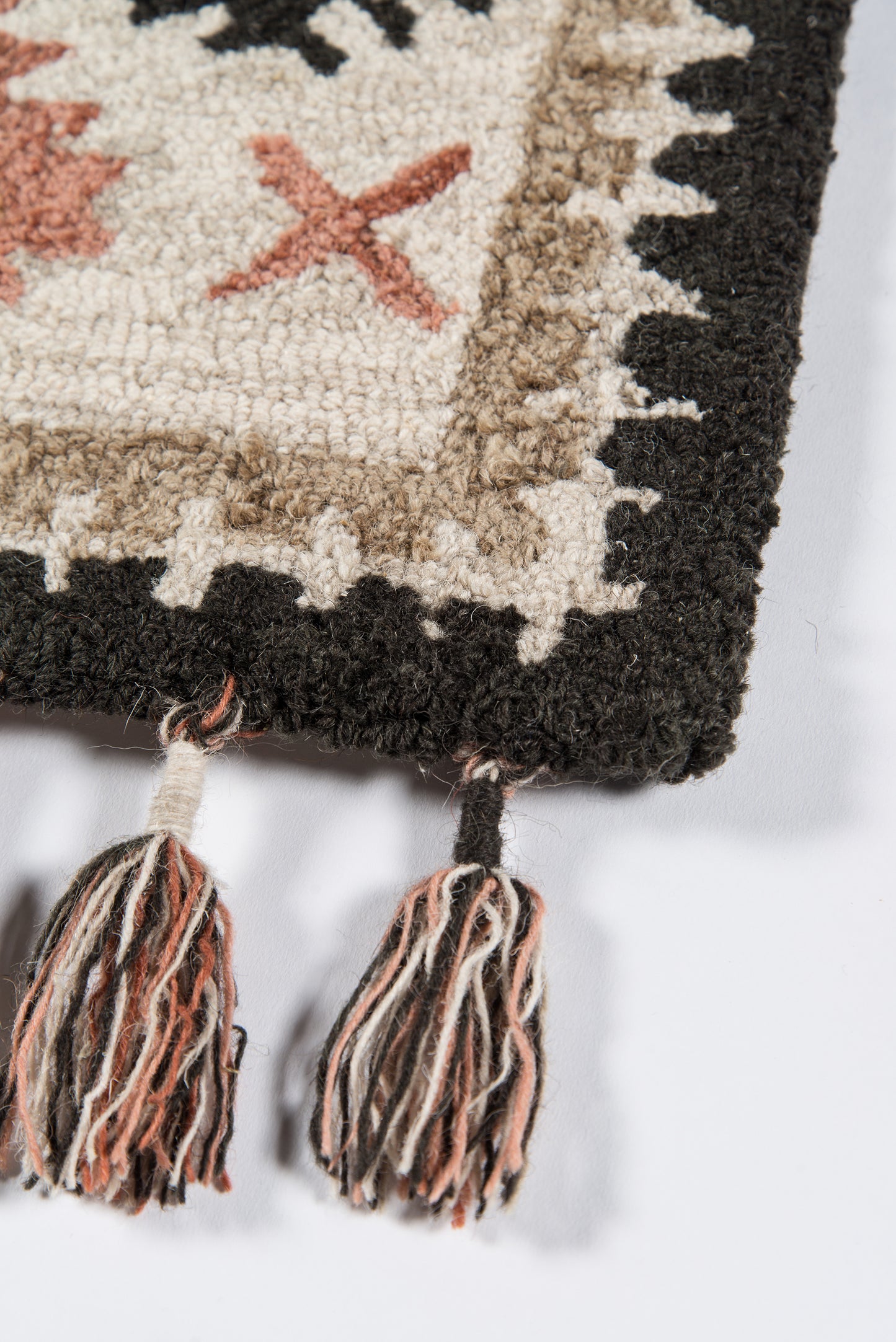 Woven rug with cream center, beige-brown border, black edge, orange X motif & multi-color tassel fringe, 7'6" x 9'6