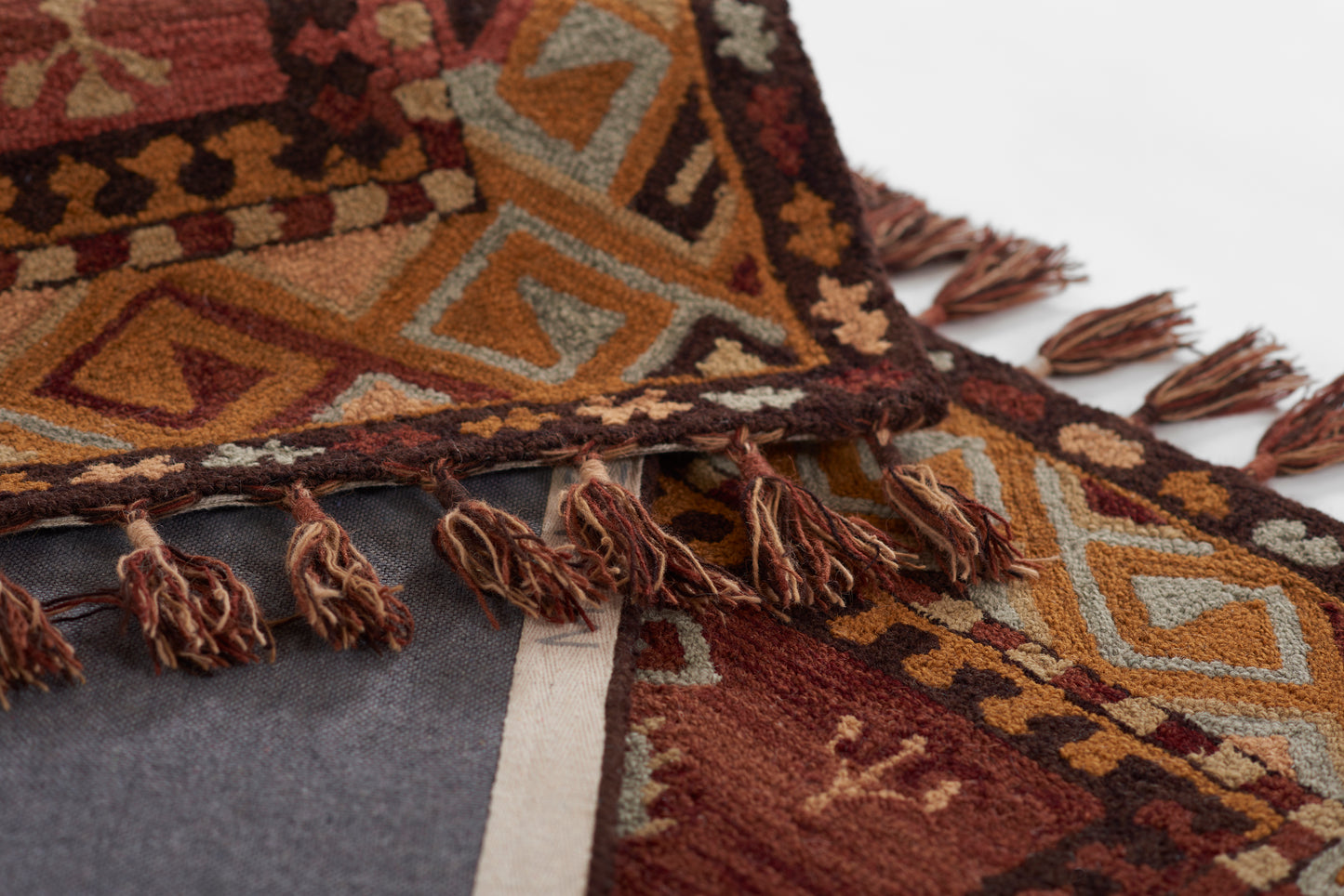 Geometric tribal rug in rust, orange, brown and teal with triangles and diamonds patterns and tassel fringe.