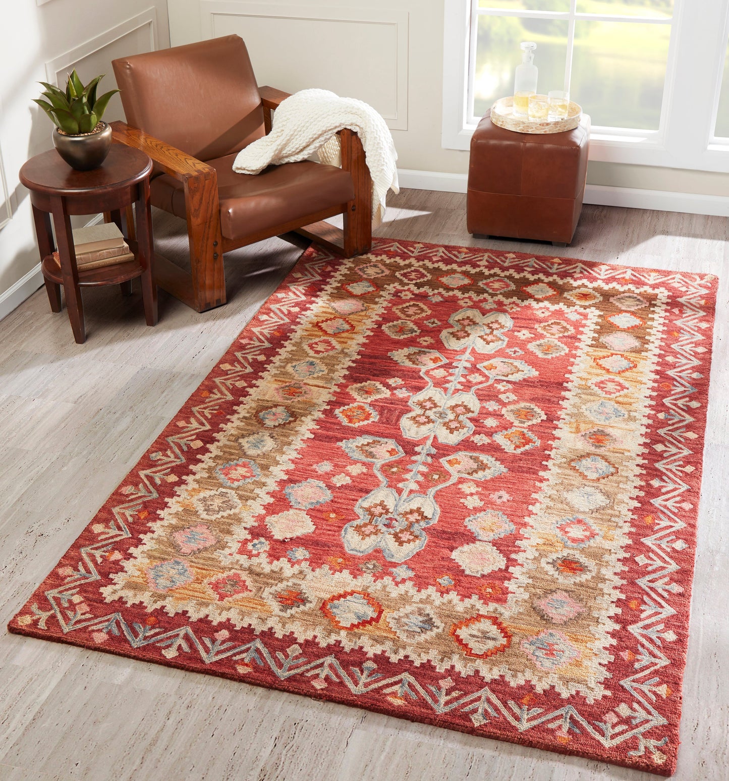 Red kilim-style area rug with ivory border and multicolored geometric and floral motifs.