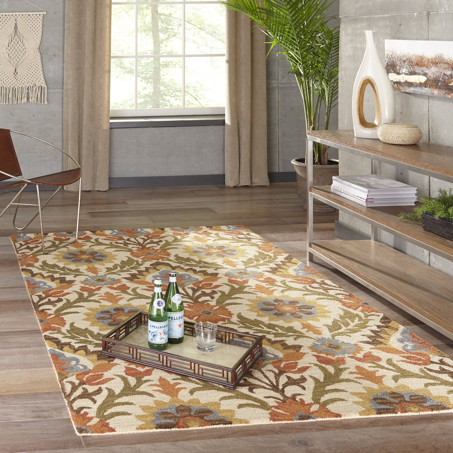 Boho floral area rug in beige, orange, blue and green; metal tray with bottles rests on it in a modern rustic living room.