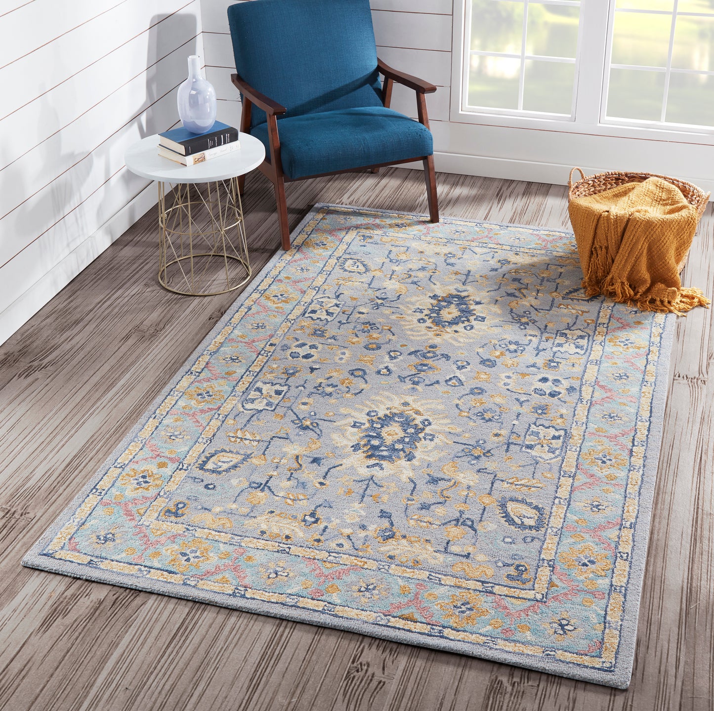 Blue floral area rug with beige and yellow accents in a modern living space with a blue upholstered chair.