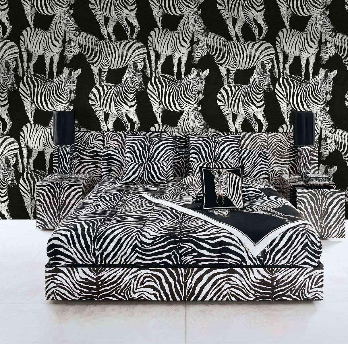 Black-and-white zebra print bedding with matching upholstered bed and sofa, against zebra-pattern wallpaper.