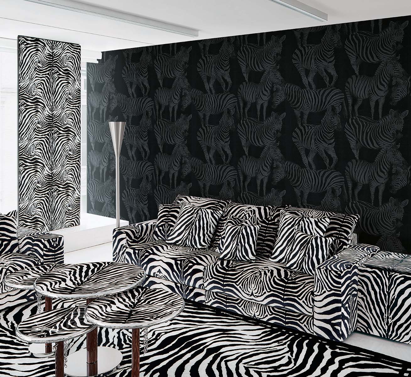 Zebra-print living room with black zebra wallpaper, zebra-pattern sofa and cushions, zebra rug, and round tables.