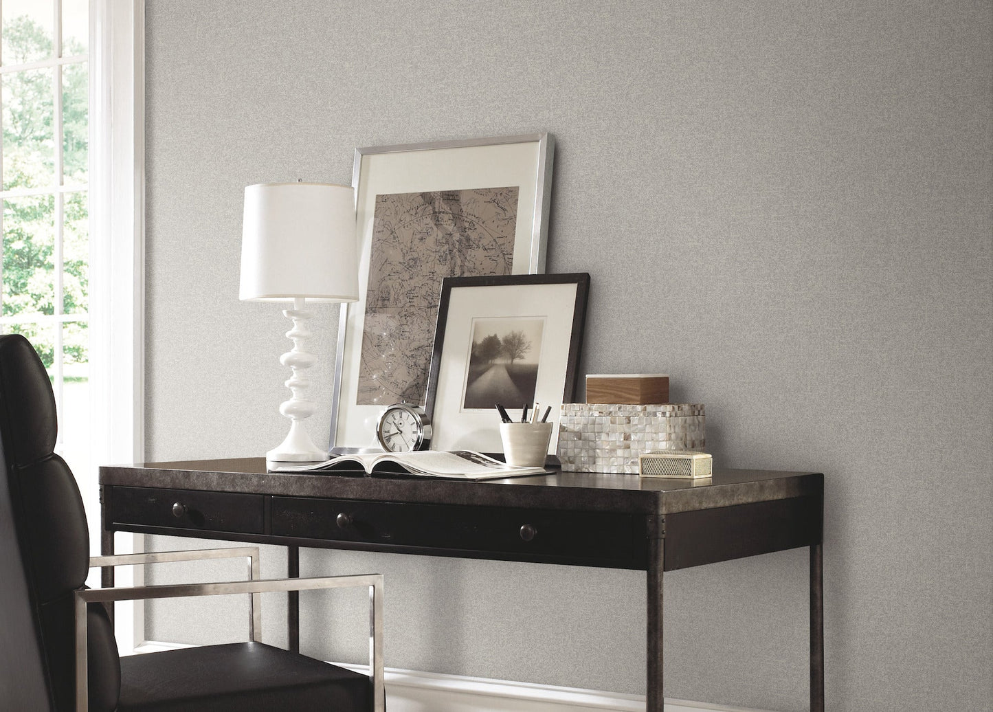 Wall covered in black textured wallpaper with a subtle pattern; white lamp and framed photos visible nearby.