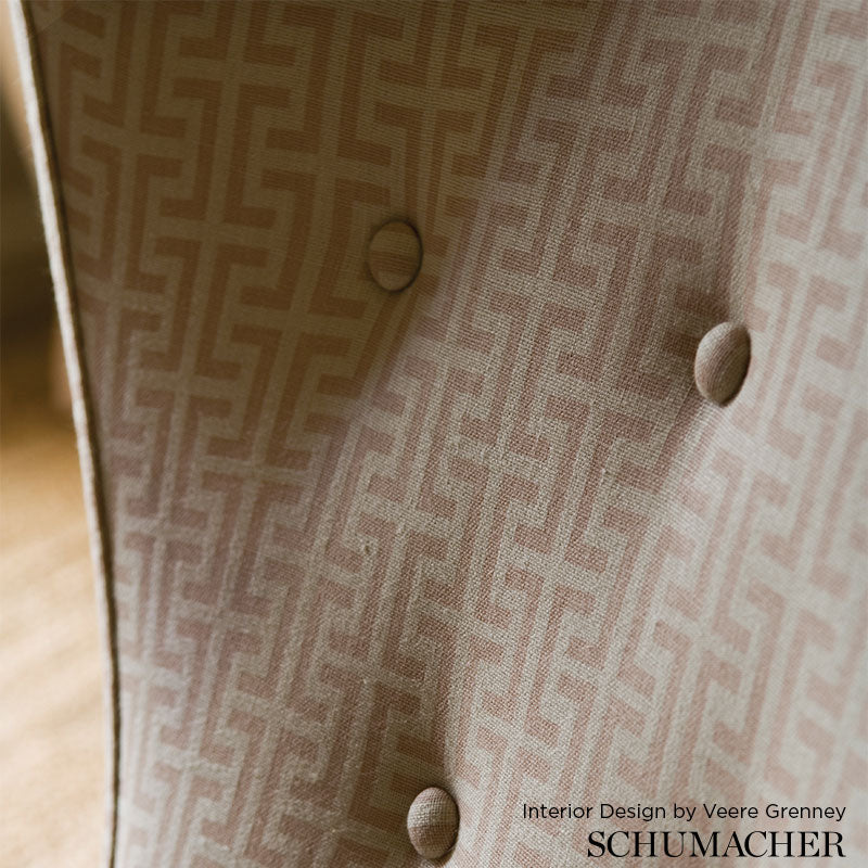 Tan fabric with repeating Greek-key pattern, tufted with round fabric-covered buttons; interior design credit text visible.