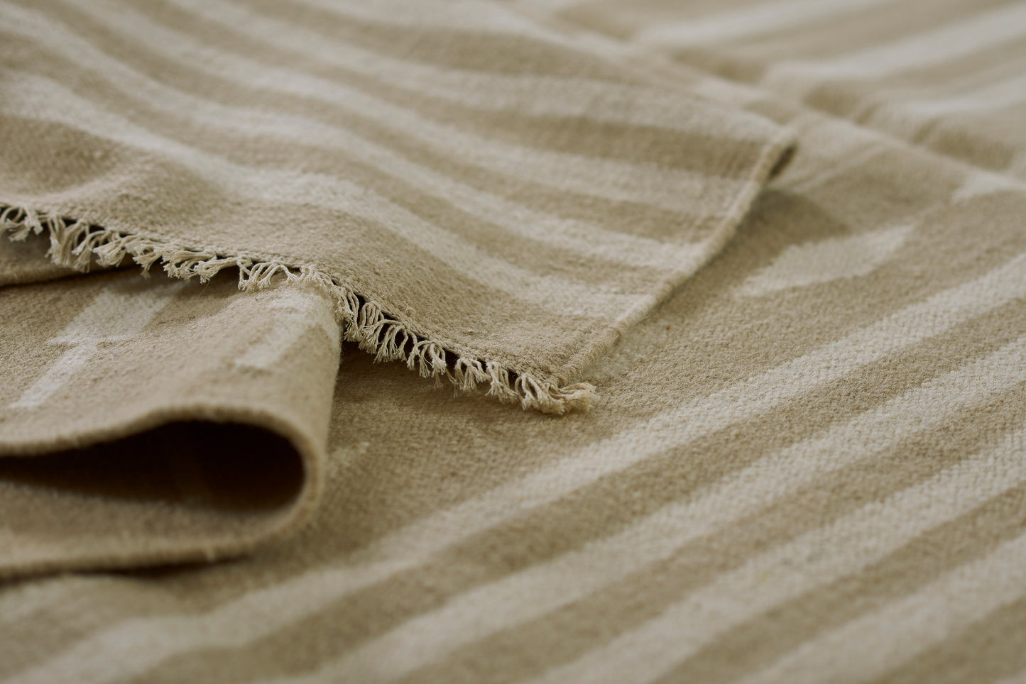 Beige and cream striped woven rug with fringed edges, 9' x 12'.