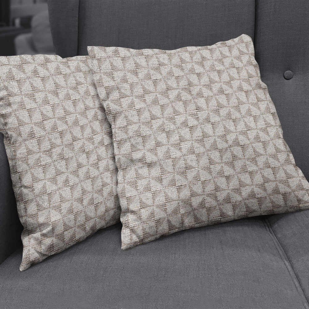 Two beige geometric-patterned throw pillows on a gray sofa, in Dove geometric fabric.