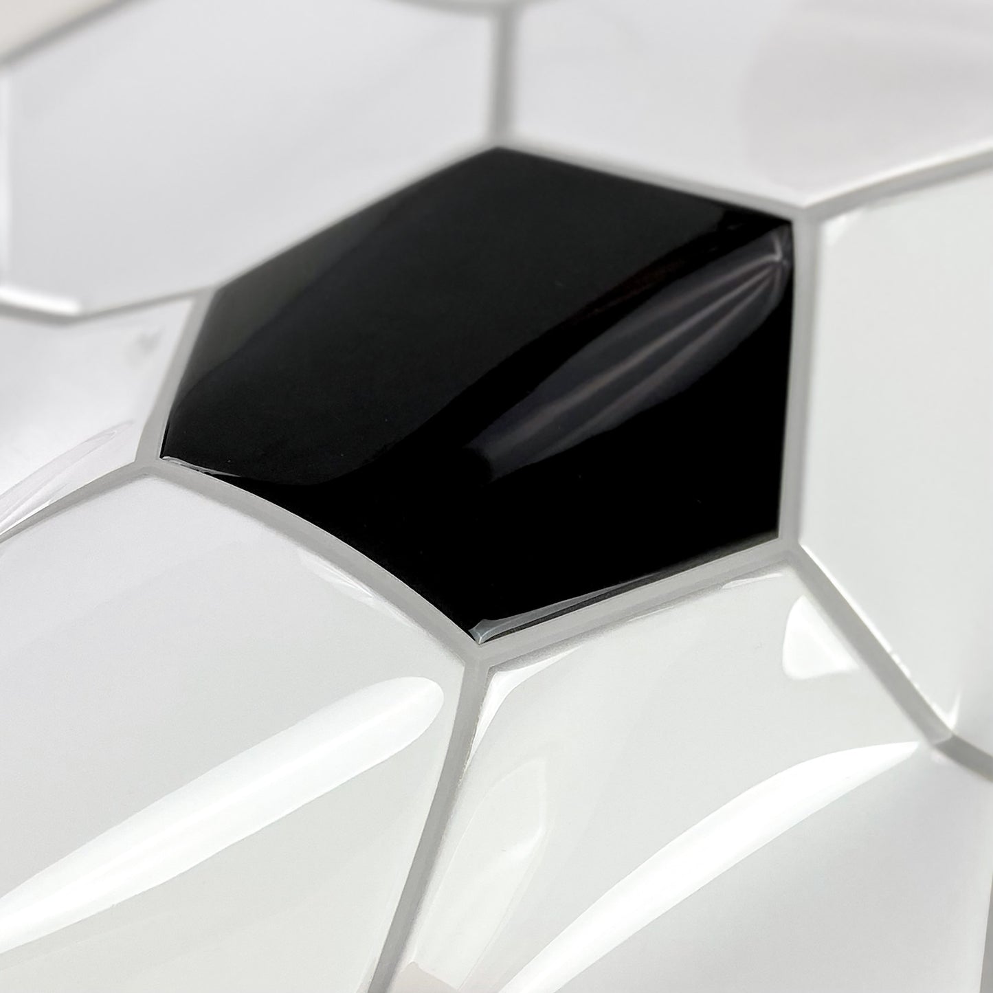 Close-up of glossy white hexagonal wallpaper with a single black hexagon accent
