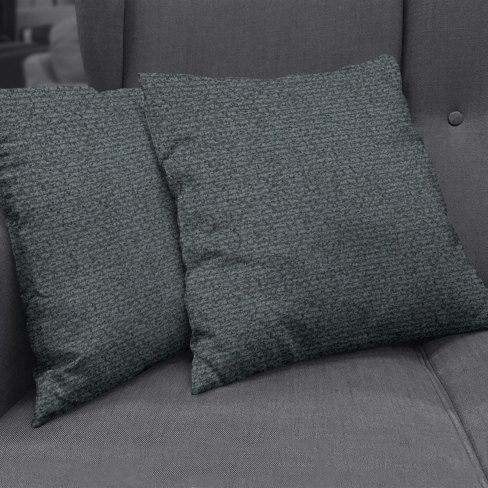 Two square dark teal textured boucle throw pillows on a charcoal sofa.