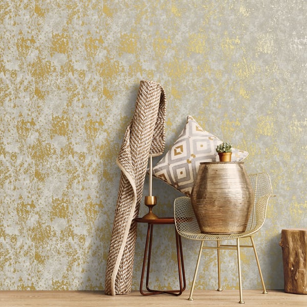 Beige knit throw over a wooden side table with geometric pillow and a gold ribbed vase with a cactus, beside a metal chair.