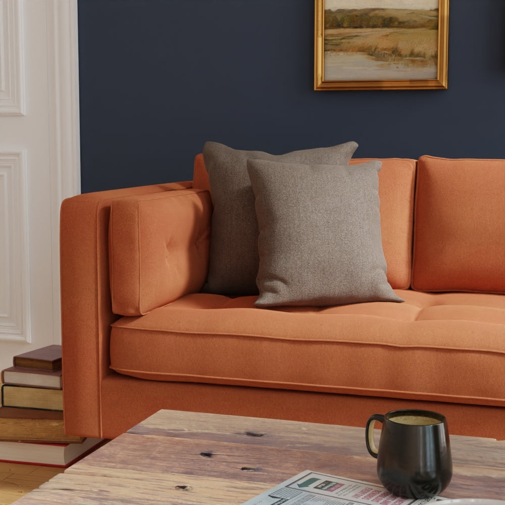 Orange fabric sofa with gray cushions on a dark navy wall; wooden coffee table with a mug and a newspaper.