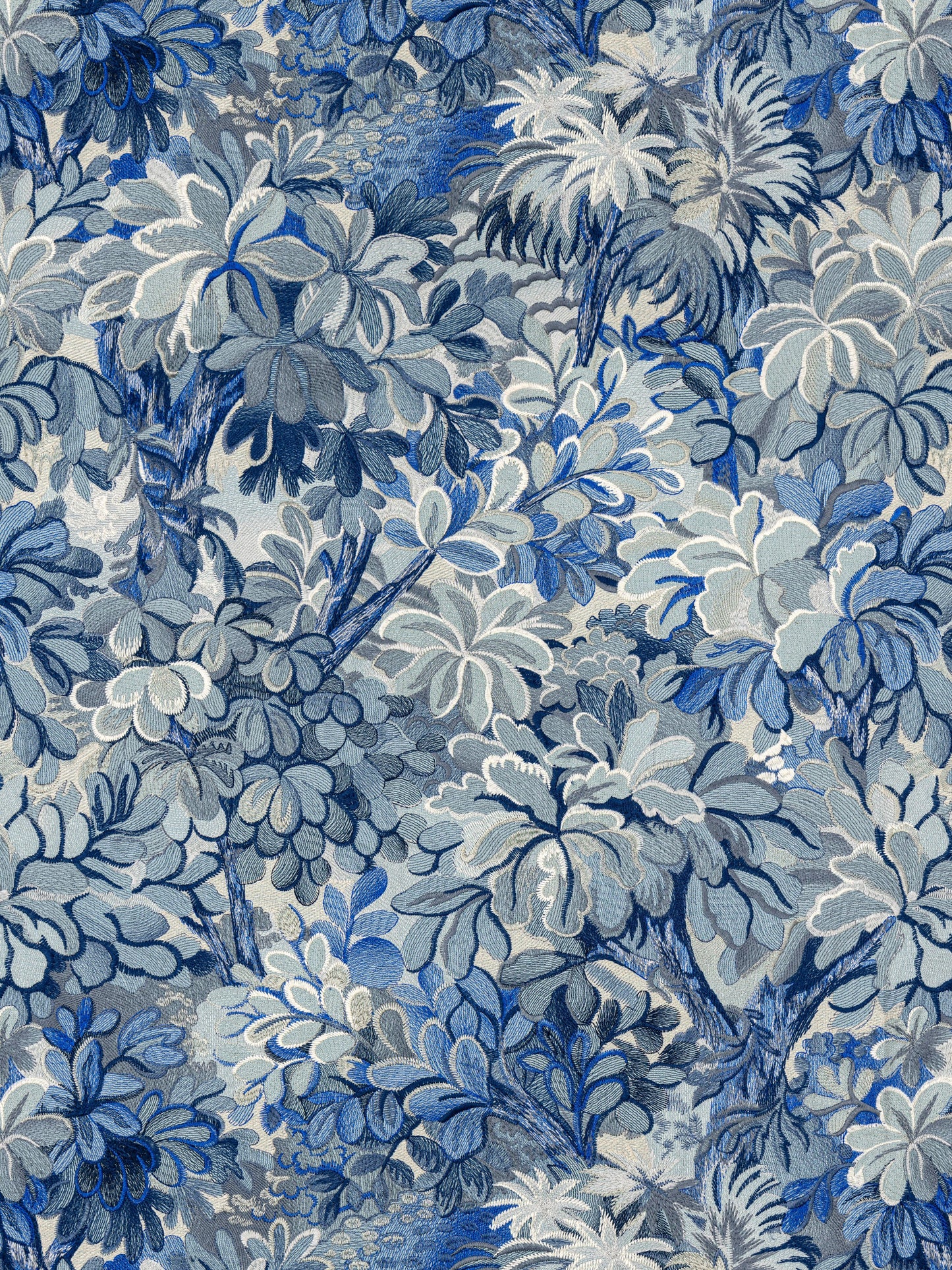 Blue botanical floral fabric with layered leaves in navy, sky blue, and gray tones; tapestry-style pattern.